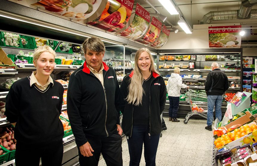 Butikkpersonale står foran frukt- og grøntavdelingen i en dagligvarebutikk.