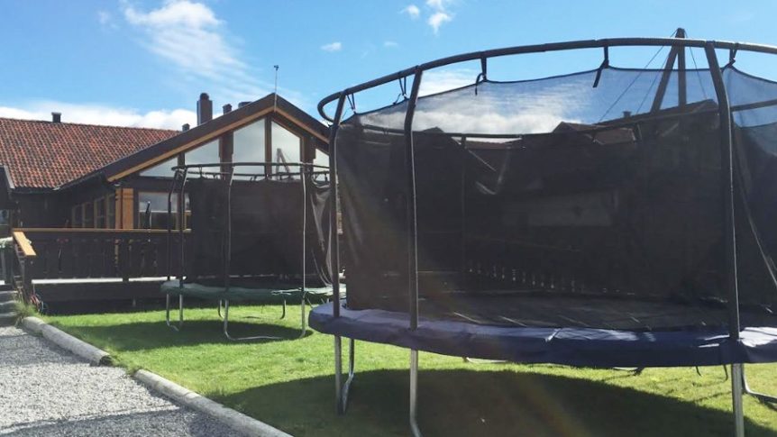 To trampoliner i en hage ved siden av et trehus med blå himmel. Perfekt for sommermoro utendørs.
