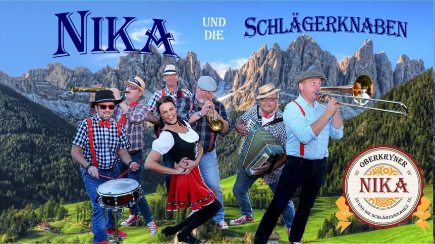 Musikkgruppe spiller folkemusikk i alpelandskap, fargerike klær, tradisjonelle instrumenter, fjell i bakgrunnen.