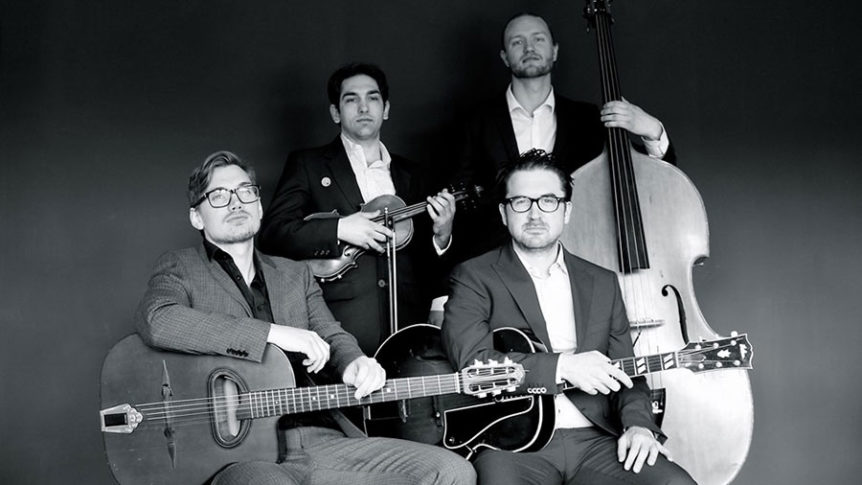 Fire menn i dress spiller musikkinstrumenter: gitarer, fiolin og kontrabass, i et studio i svart-hvitt.