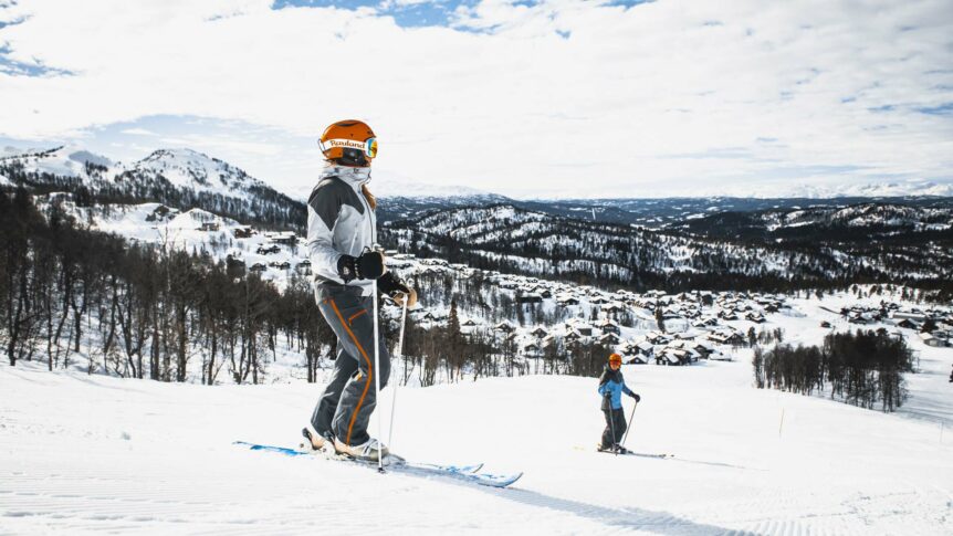To personer står på ski med vakker vinterbakgrunn i fjellet.