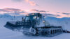 Snøplog på fjellandskap i solnedgang, klar for å rydde snødekte veier i vinternaturen.