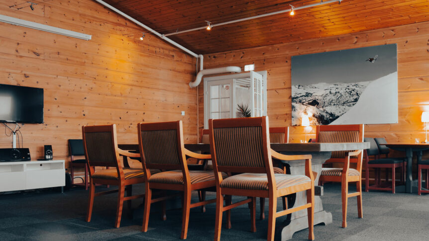 Moderne møterom i treverk med komfortable stoler og fjellfotografi på veggen.