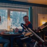 Familie spiser middag på restaurant med utsikt over snødekt landskap gjennom vinduet.