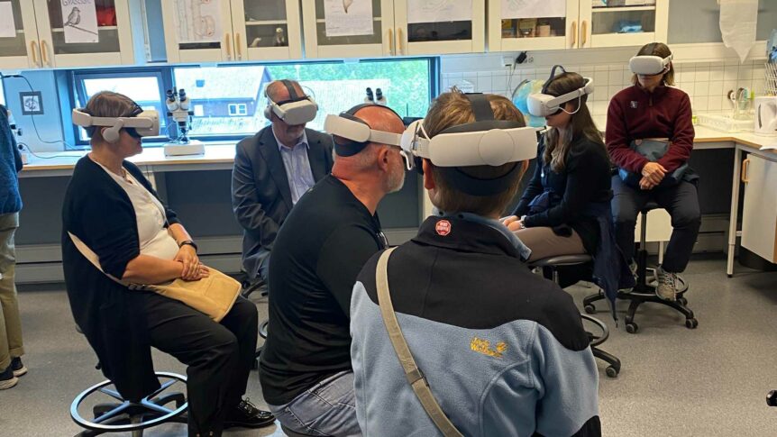 Gruppe voksne i VR-briller som opplever virtuell virkelighet i et klasserom.