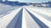 Solspeilet snødekte fjellandskap med ferske skispor, perfekt for langrenn i klar vinterdag.