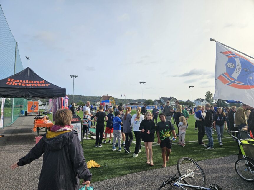Folk samles på en utendørs festival ved Rauland Skisenter med boder og aktiviteter i solfylt vær.