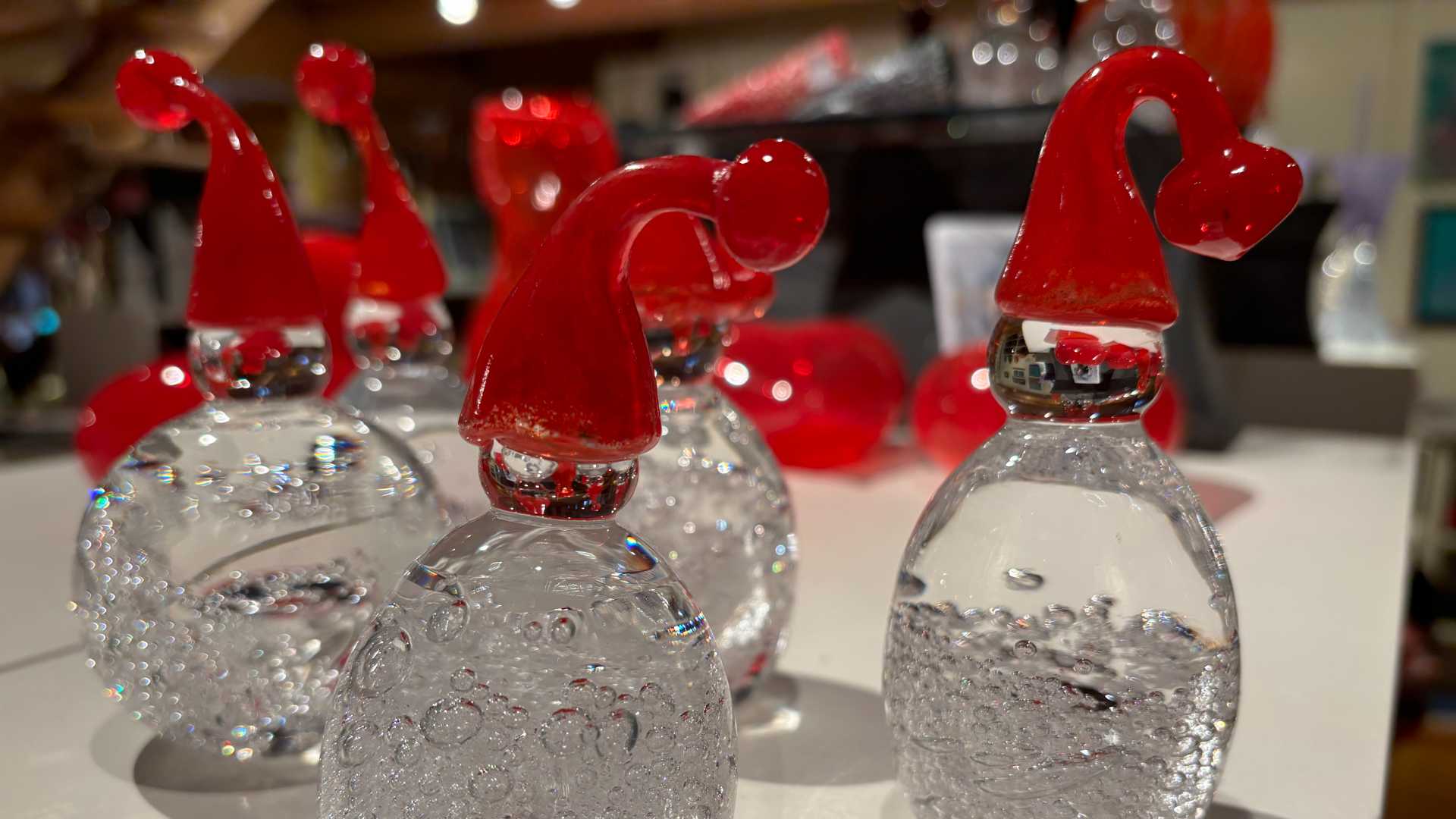 Glassnisser med røde luer på et bord, perfekt for juledekorasjon.