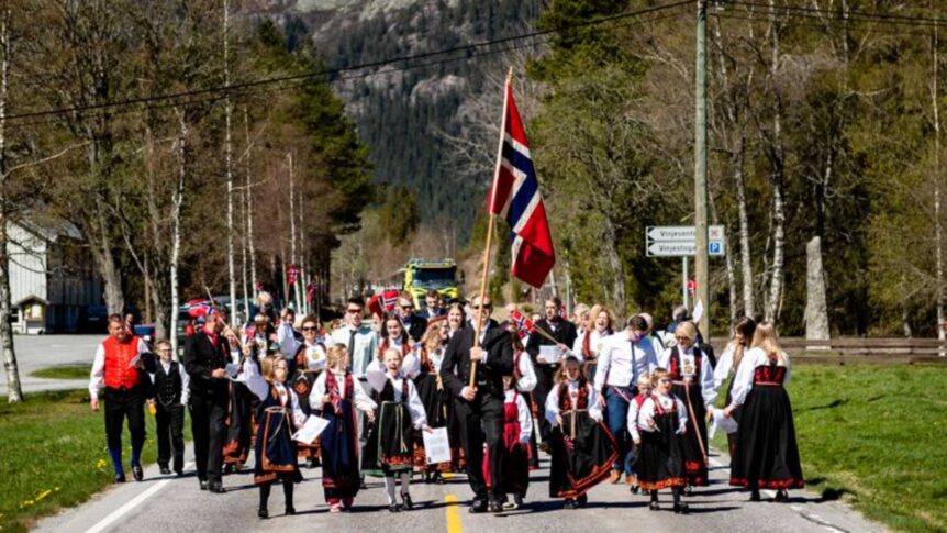 Parade i Norge med folk i bunader som bærer et norsk flagg.