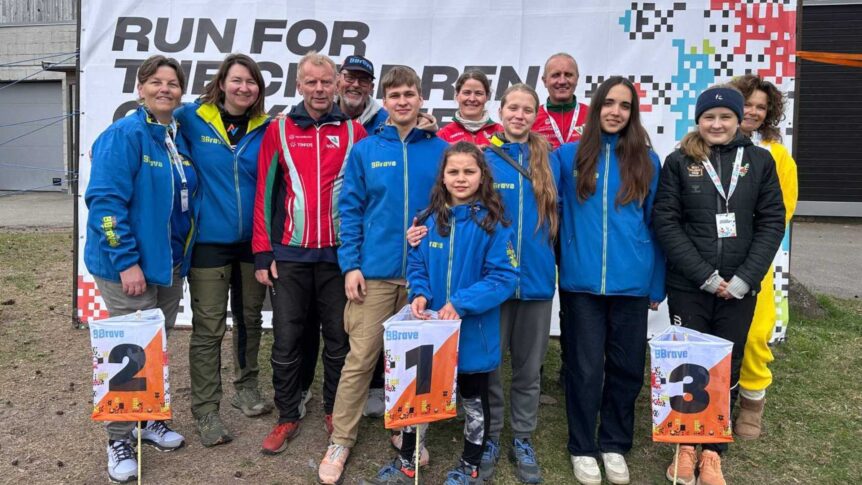 Gruppebilde av personer i blå jakker foran et skilt med teksten Run for the children.