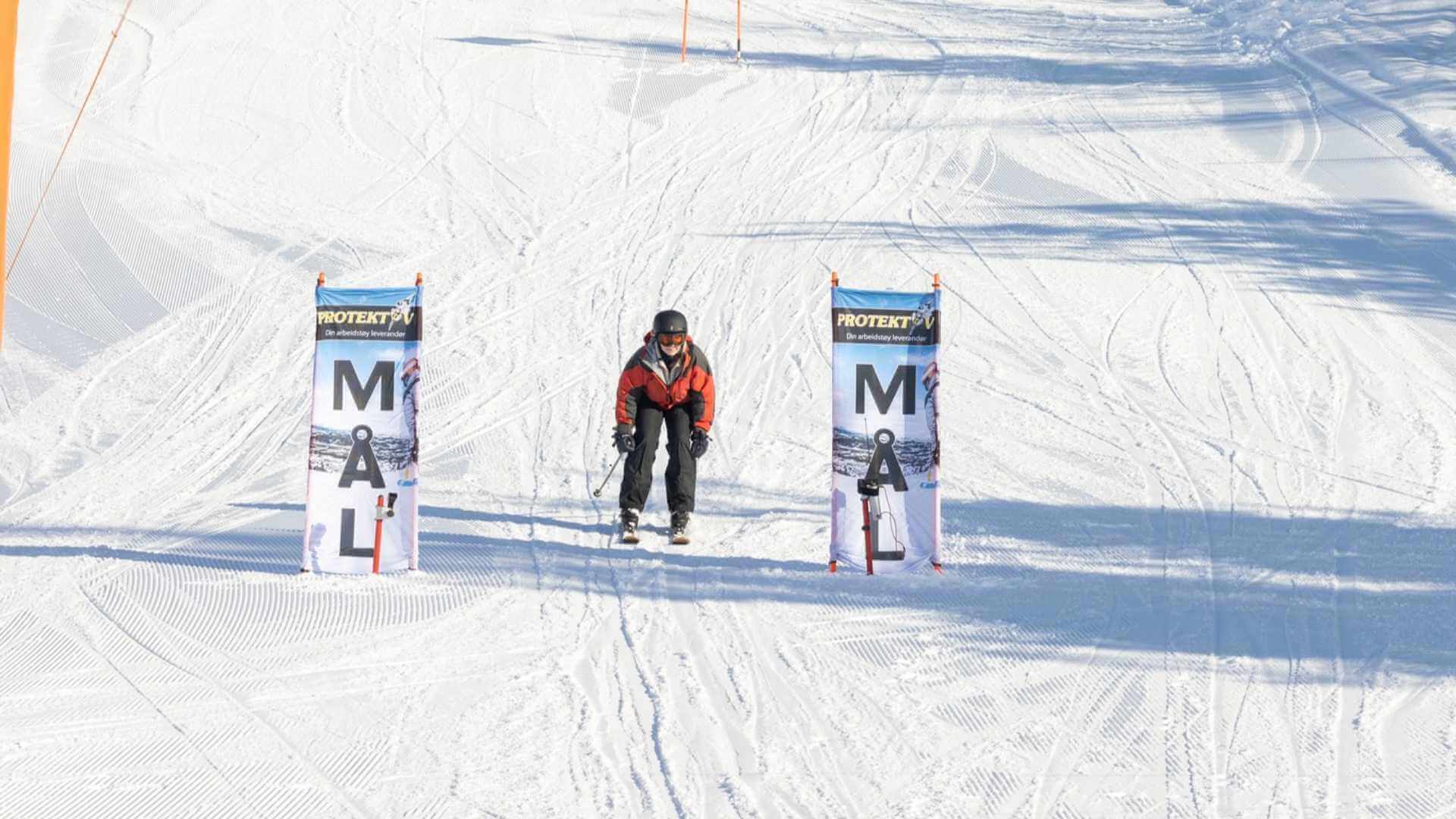Person på ski når målstreken i solfylt vinterlandskap.