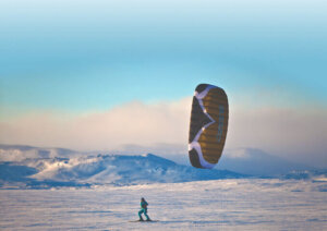 Kitesurfing på snødekt vidde med blå himmel i bakgrunnen, vintereventyr i Norge.
