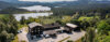 Panorama av hus ved innsjø omgitt av skog og fjell i et norsk landskap.