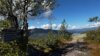 Utsikt fra dansersteinen med skilting om historien, omgivelsene og fjellene i bakgrunnen. Blå himmel og skyer.