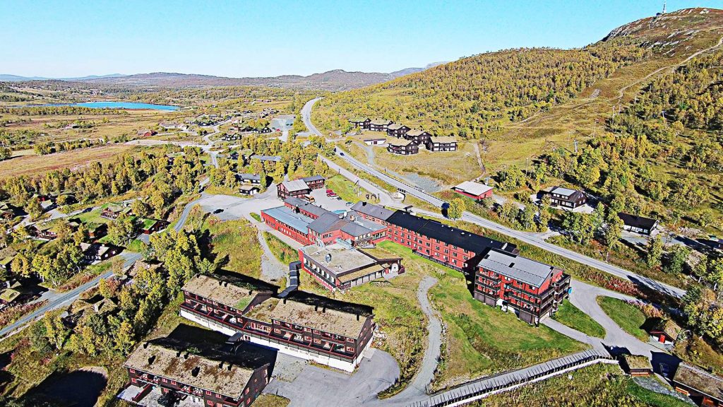 Luftfoto av fjellandskap med hytter og hotell i skogkledd dal, vakker utsikt og klar himmel i Norge.