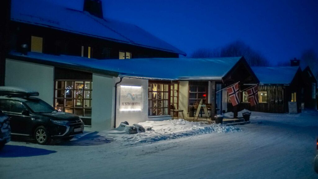 Utvendig vinterkveld ved Austlid Fjellstue med norske flagg og snødekkede omgivelser.